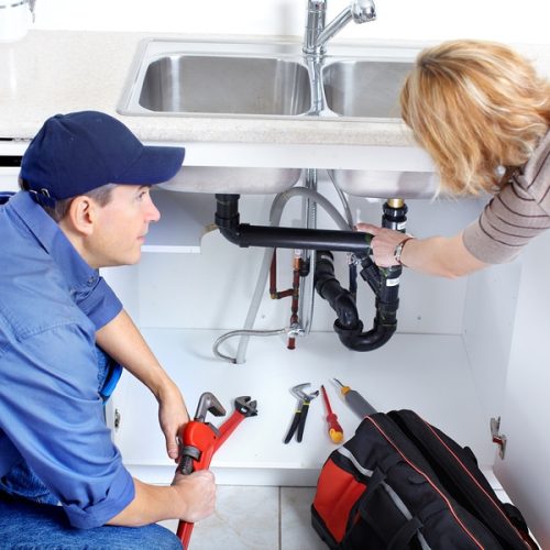 Plumber Mature plumber fixing a sink at kitchen